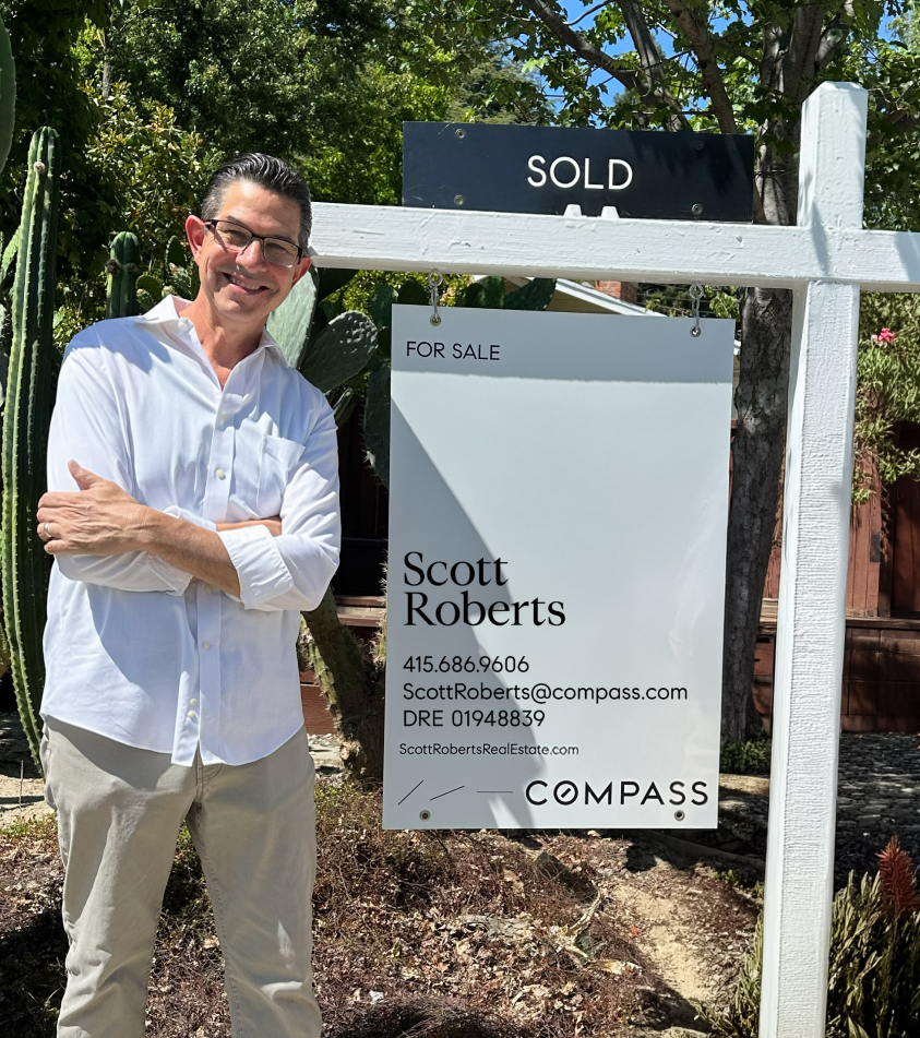 Scott Roberts in front of a sold house sign